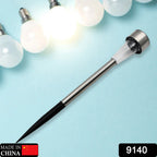 Outdoor solar lamp with a ground spike, casting a warm glow on a garden landscape.