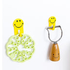 Back view of a smiley face hook, highlighting the protective peel-off adhesive film.