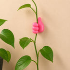 Thumb wire holder gripping plant stem along wall