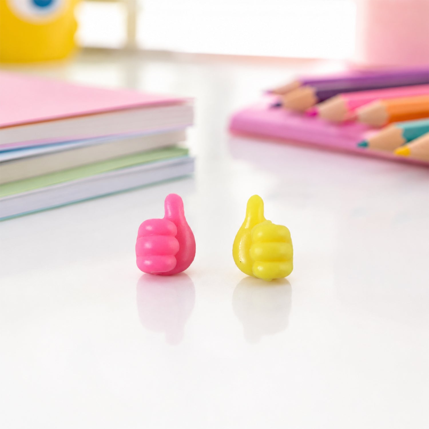 Pink and yellow thumb cable holders on study table with books