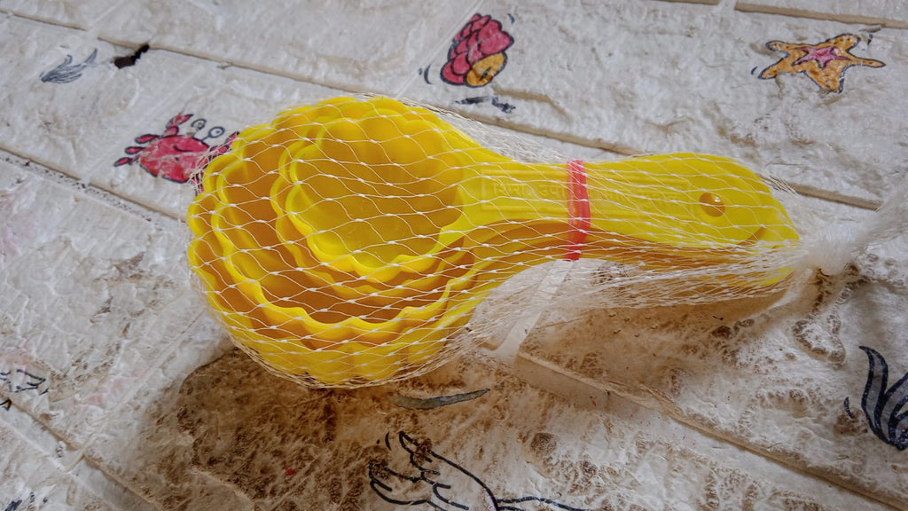 A perfectly shaped ladoo sits next to the plastic mould spoon used to create it.