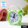 Compact quartz analog alarm clock with green transparent frame on desk