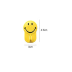 Smiley face wall hooks holding various items, showcasing their 1 kg load capacity.