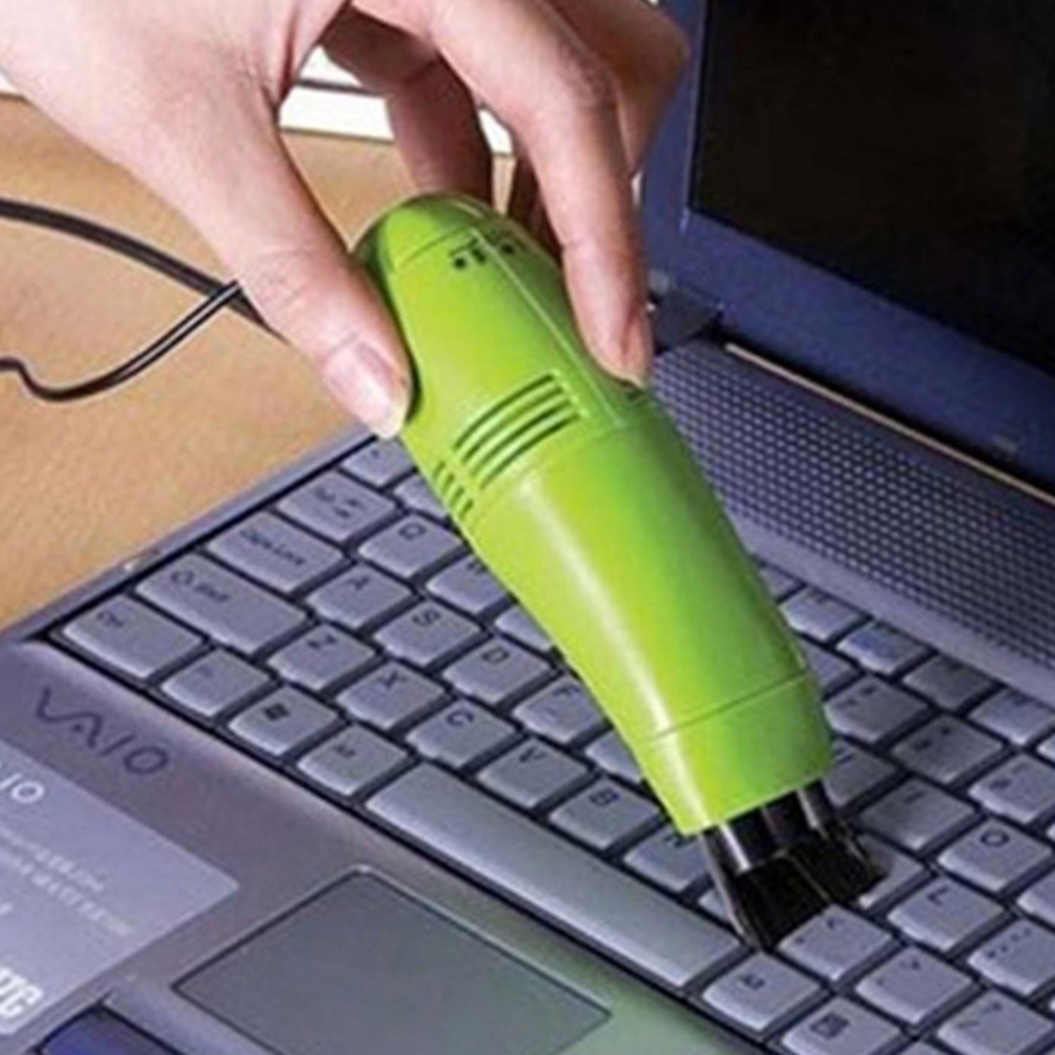 Handheld USB mini vacuum cleaner reaching tight spots in a car dashboard.