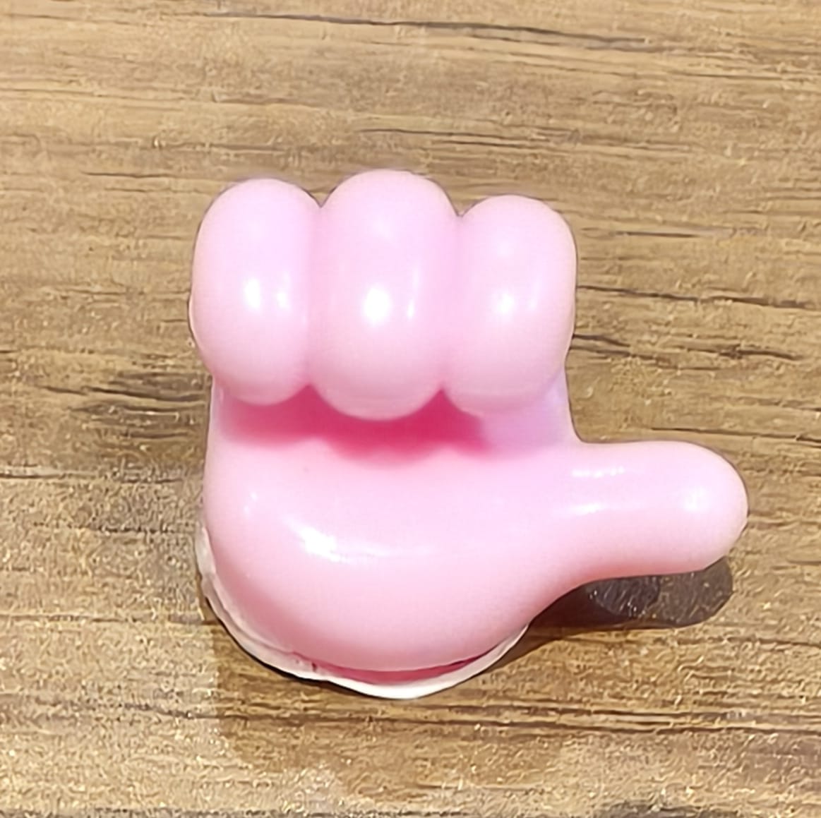 Pink silicone hand-shaped wall clip in use holding keys and charging cables