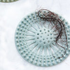 Durable silicone drain cover protecting a shower drain from clogs caused by hair.