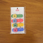 Lifestyle image of girl wearing colorful apple design hair clip set