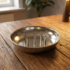 Close-up view of polished metal lotus incense stick holder with ash collection