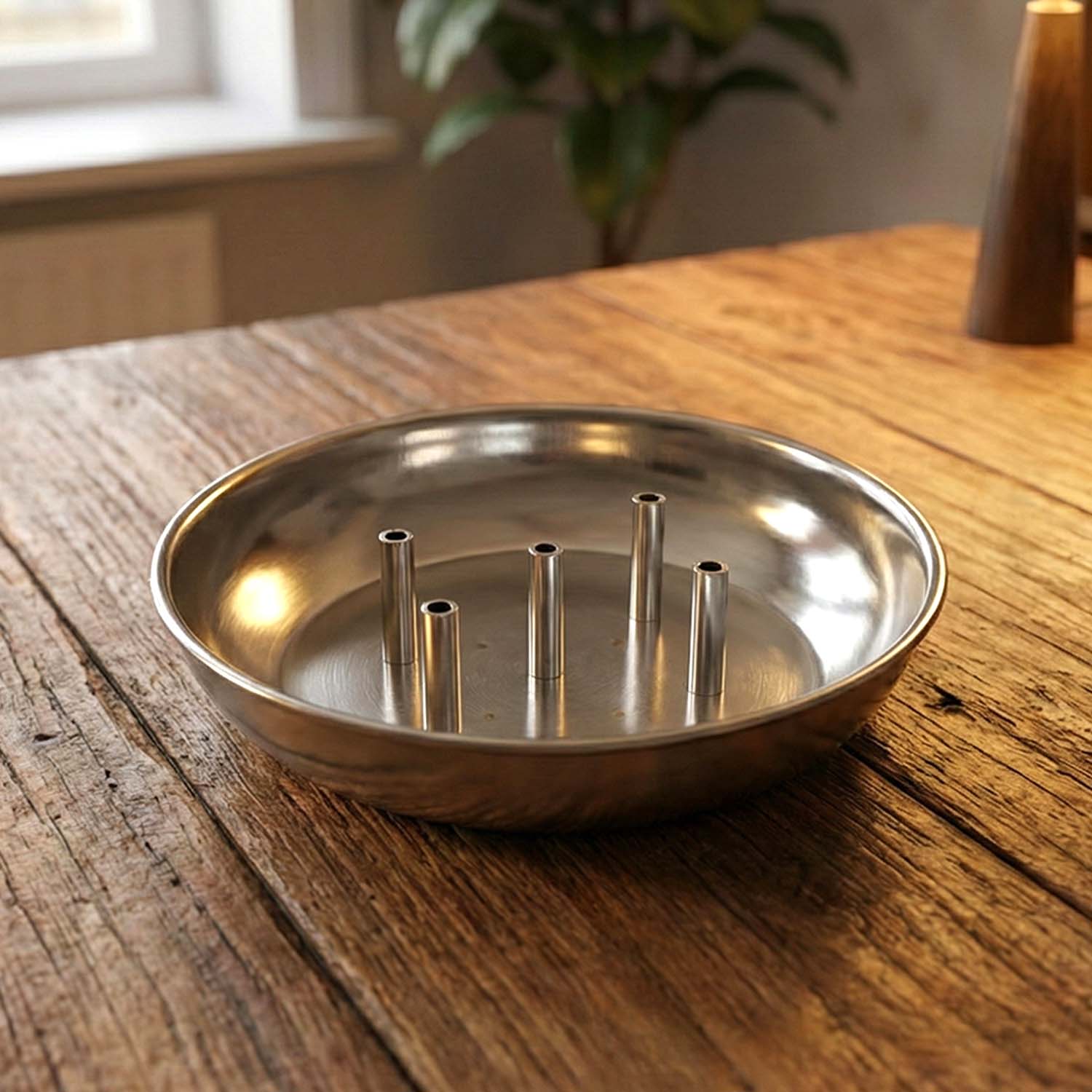 Close-up view of polished metal lotus incense stick holder with ash collection