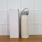 Lifestyle shot featuring the glass water bottle with phone holder in a natural setting.