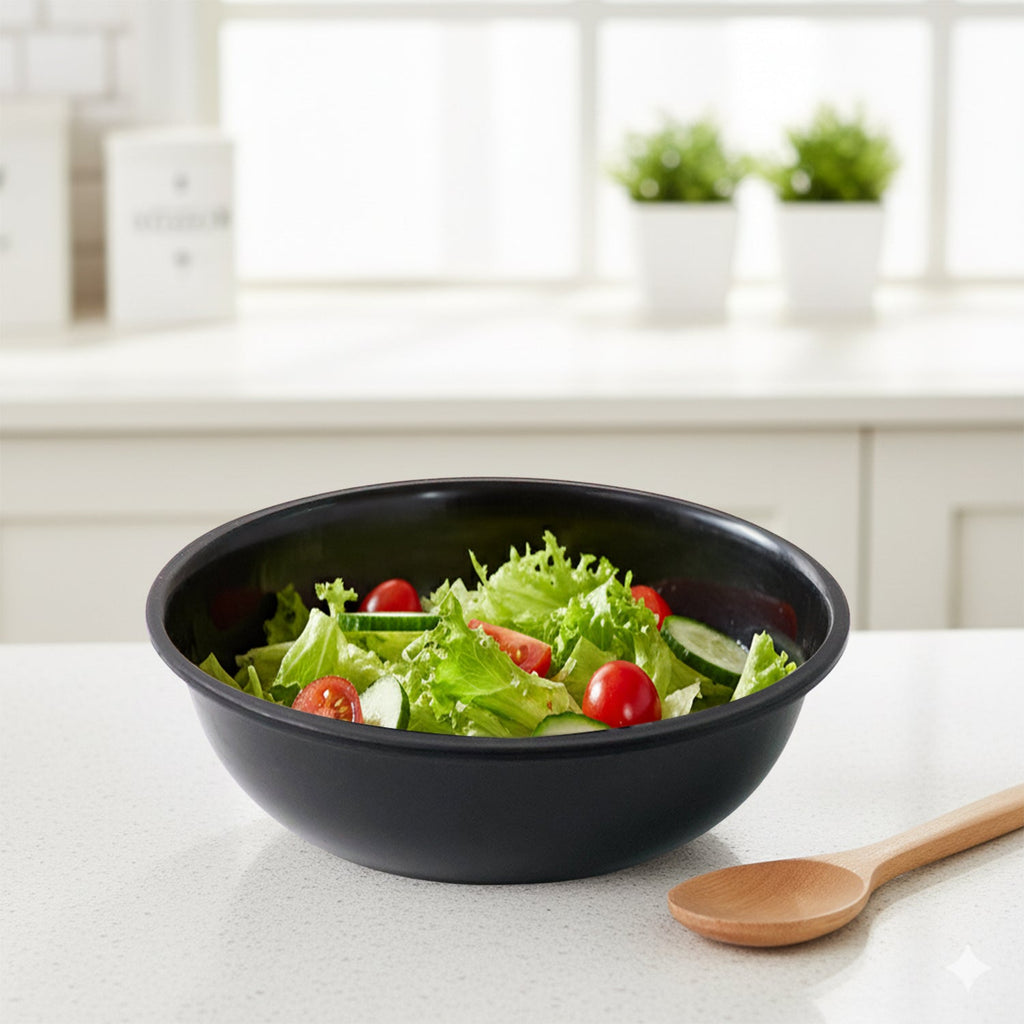 Black plastic serving bowl holding fresh salad