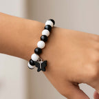 Fashionable bracelet showcasing black and white beads with cross pendant
