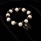 Close-up of black and white beads and cross pendant on bracelet