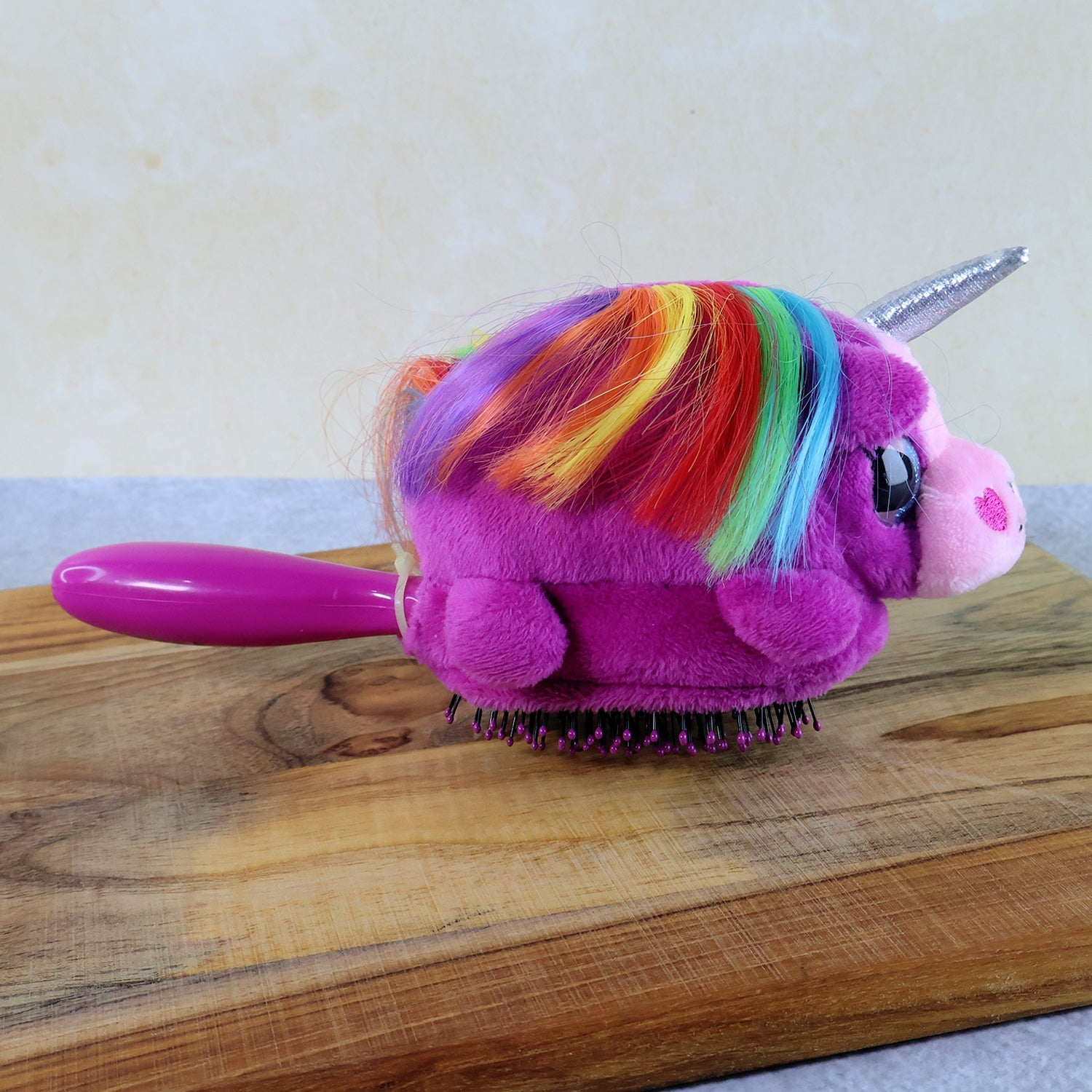 Child's hand holding the ergonomic handle of the Unicorn Detangling Hair Brush
