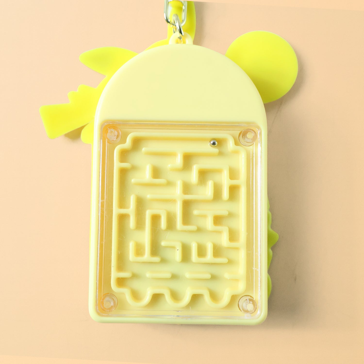 Side view of yellow cartoon character mini calculator keychain with attached bell and ring