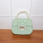 Model carrying an elegant quilted mini handbag with pearl handle and chain strap