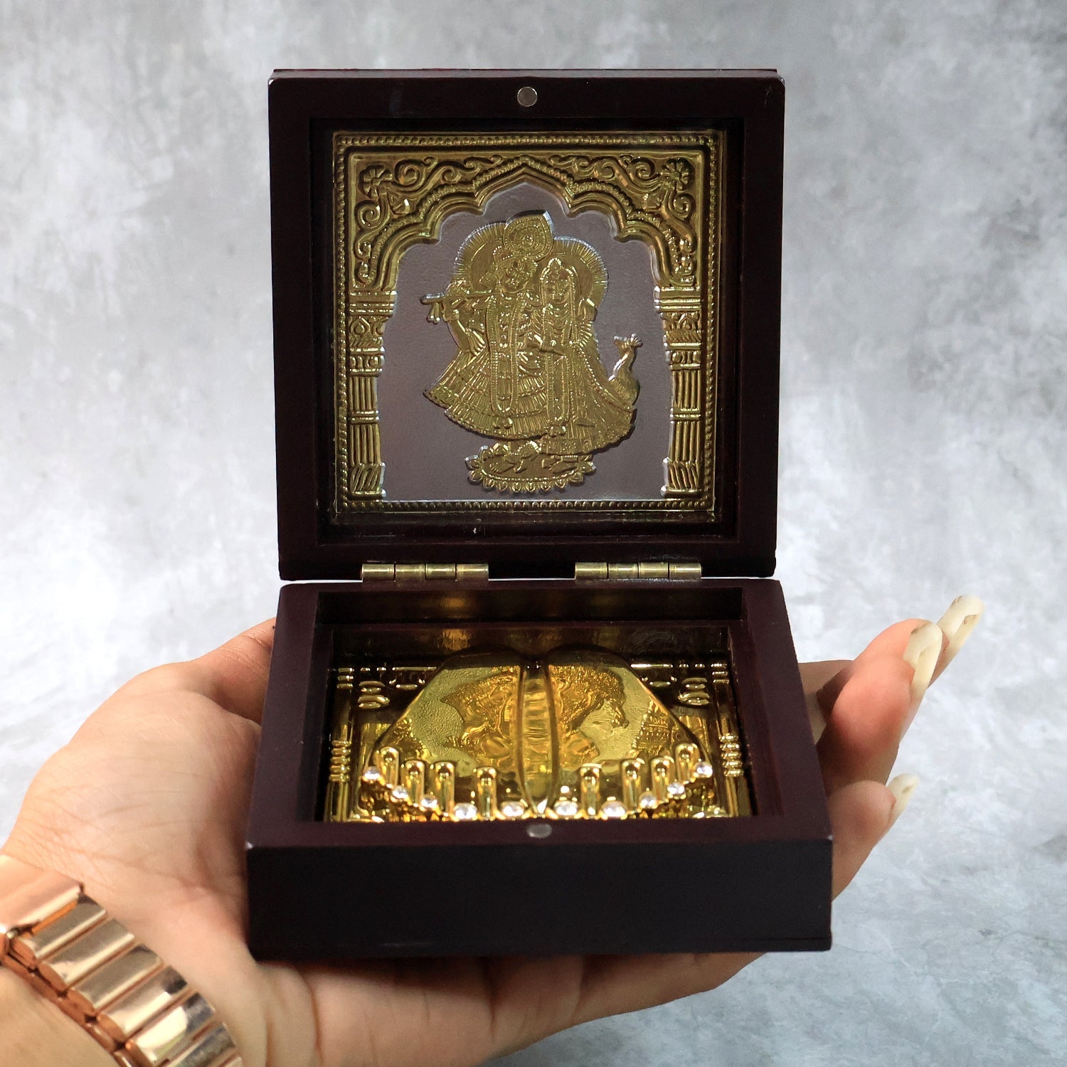 Video presenting golden Charan Paduka in wooden box used as devotional pooja accessory