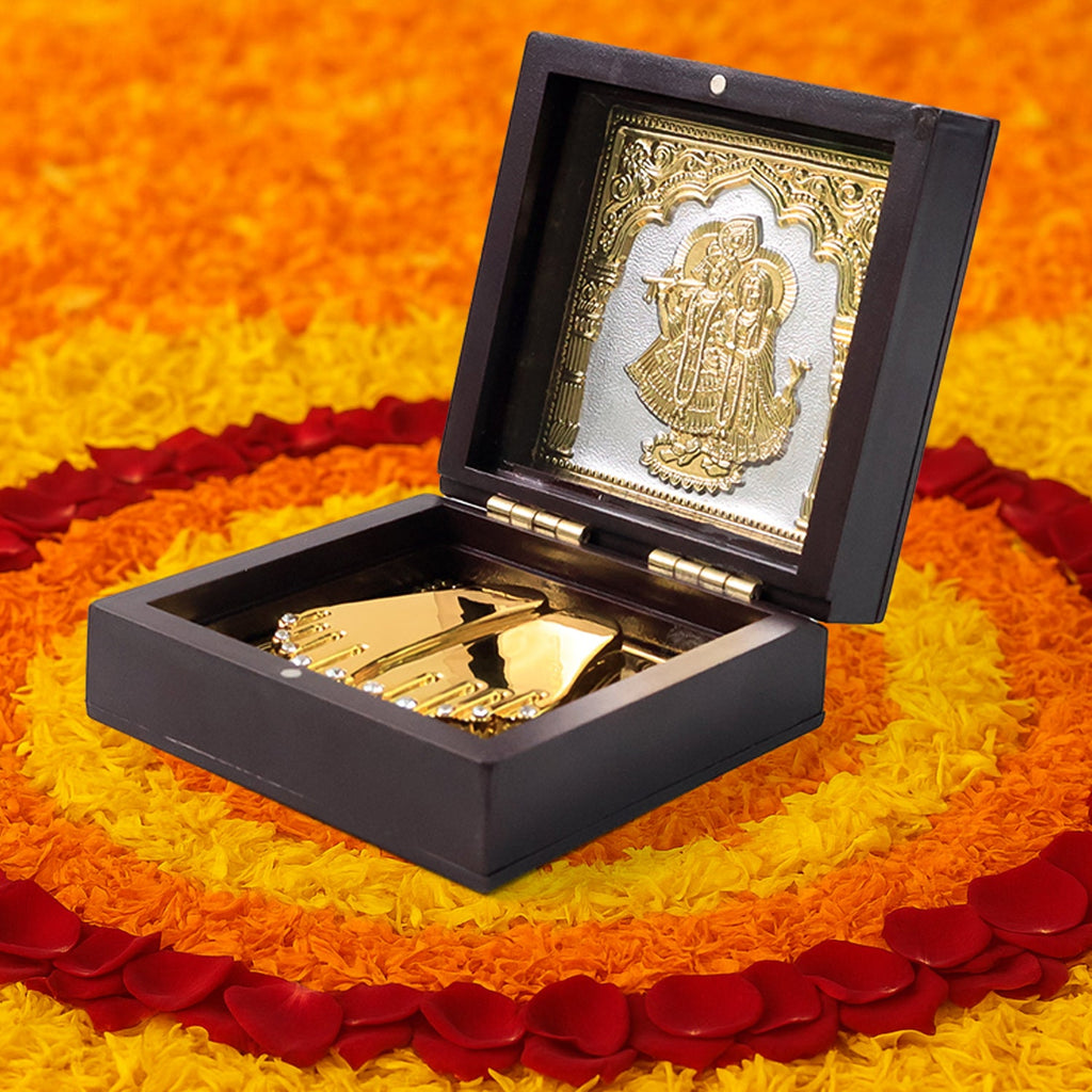 Side angle of gold-plated Charan Paduka set with ornamental Radha Krishna image on box lid