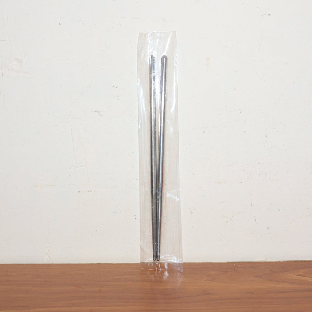 Stainless steel chopsticks actively used to pick up food during a meal.