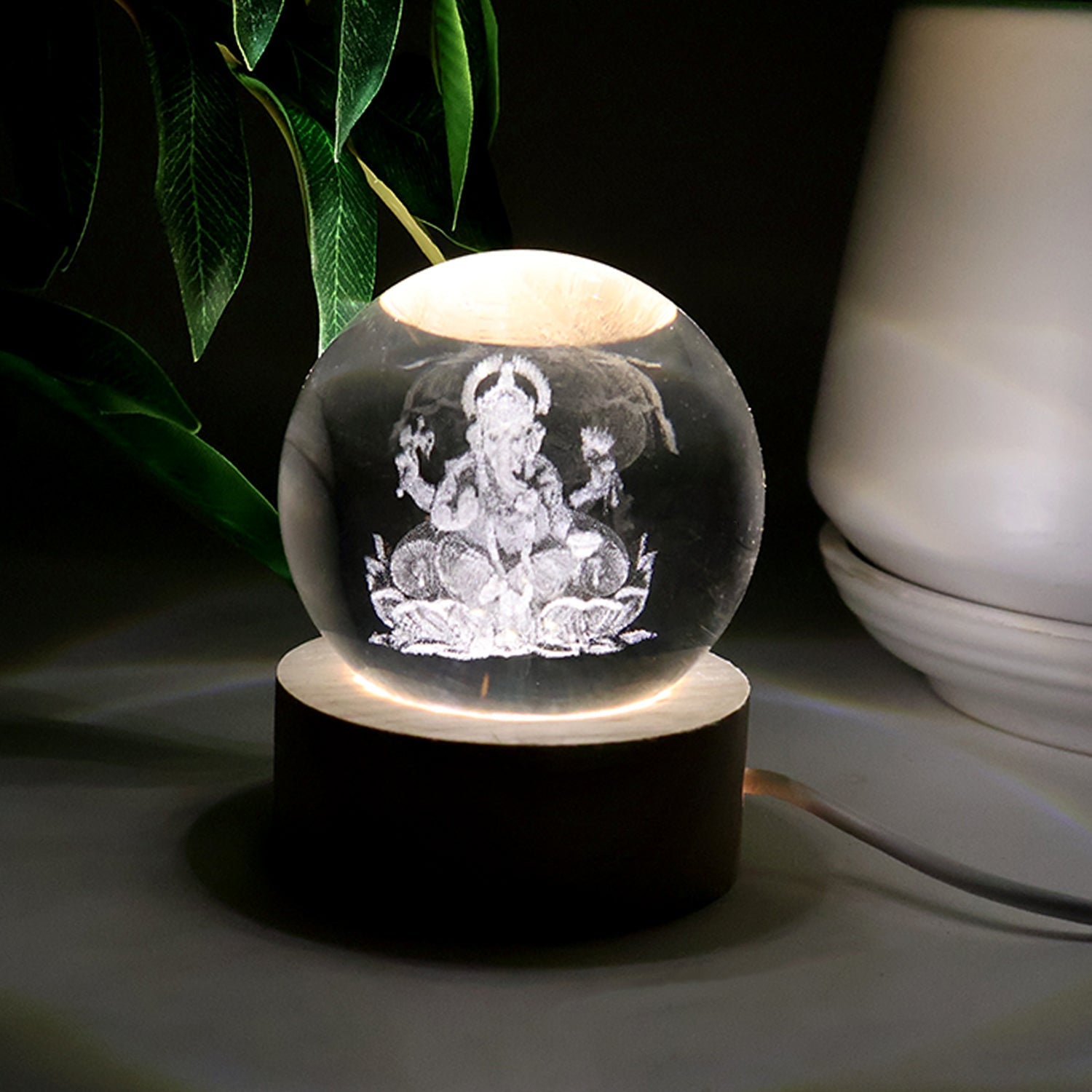 Detailed view of the illuminated 3D Ganpati idol inside the crystal ball, showing its radiant effect.
