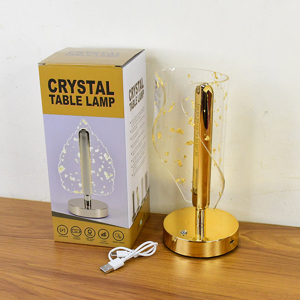 Decorative crystal table lamp glowing warmly with embedded golden leaf details