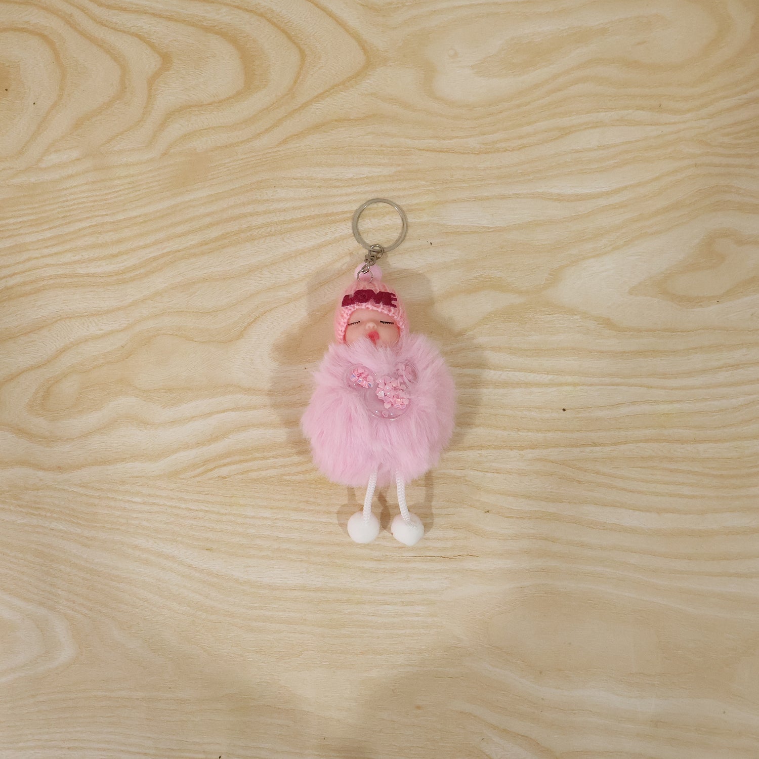 Plush doll keychain hanging on bag strap showing soft fur ball charm