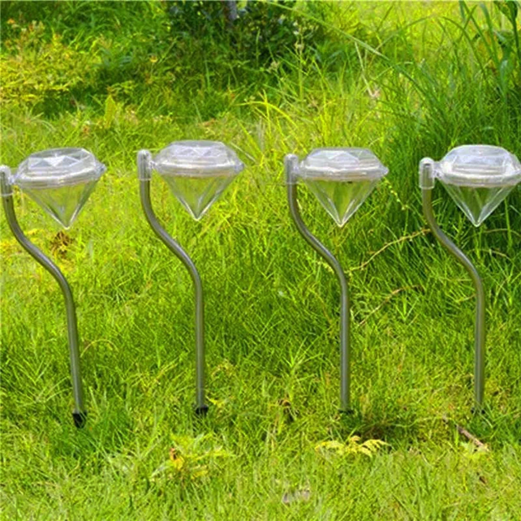 Four diamond solar garden lights creating a glowing boundary along a green lawn