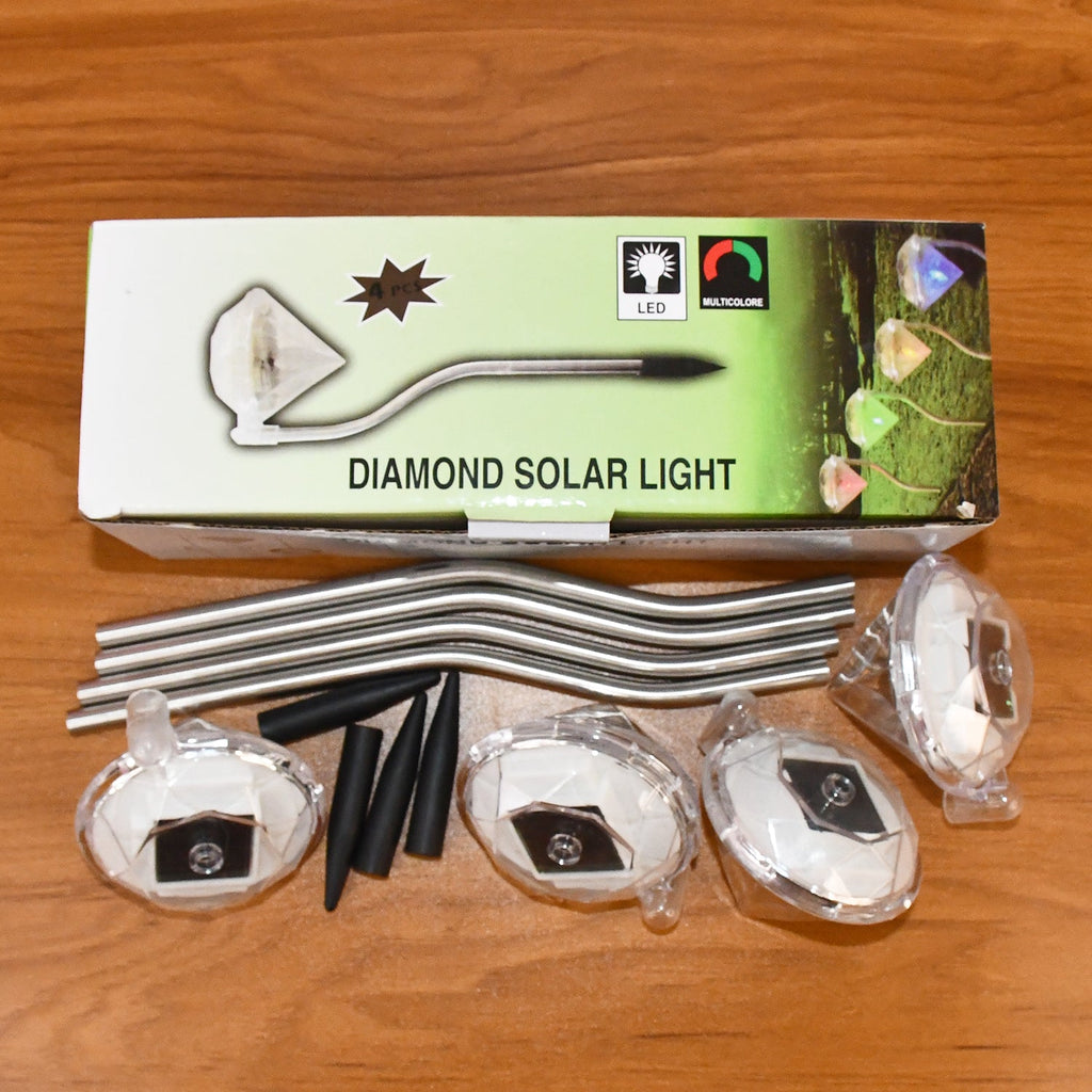 Live image of diamond solar garden lights glowing warmly in an evening garden setting