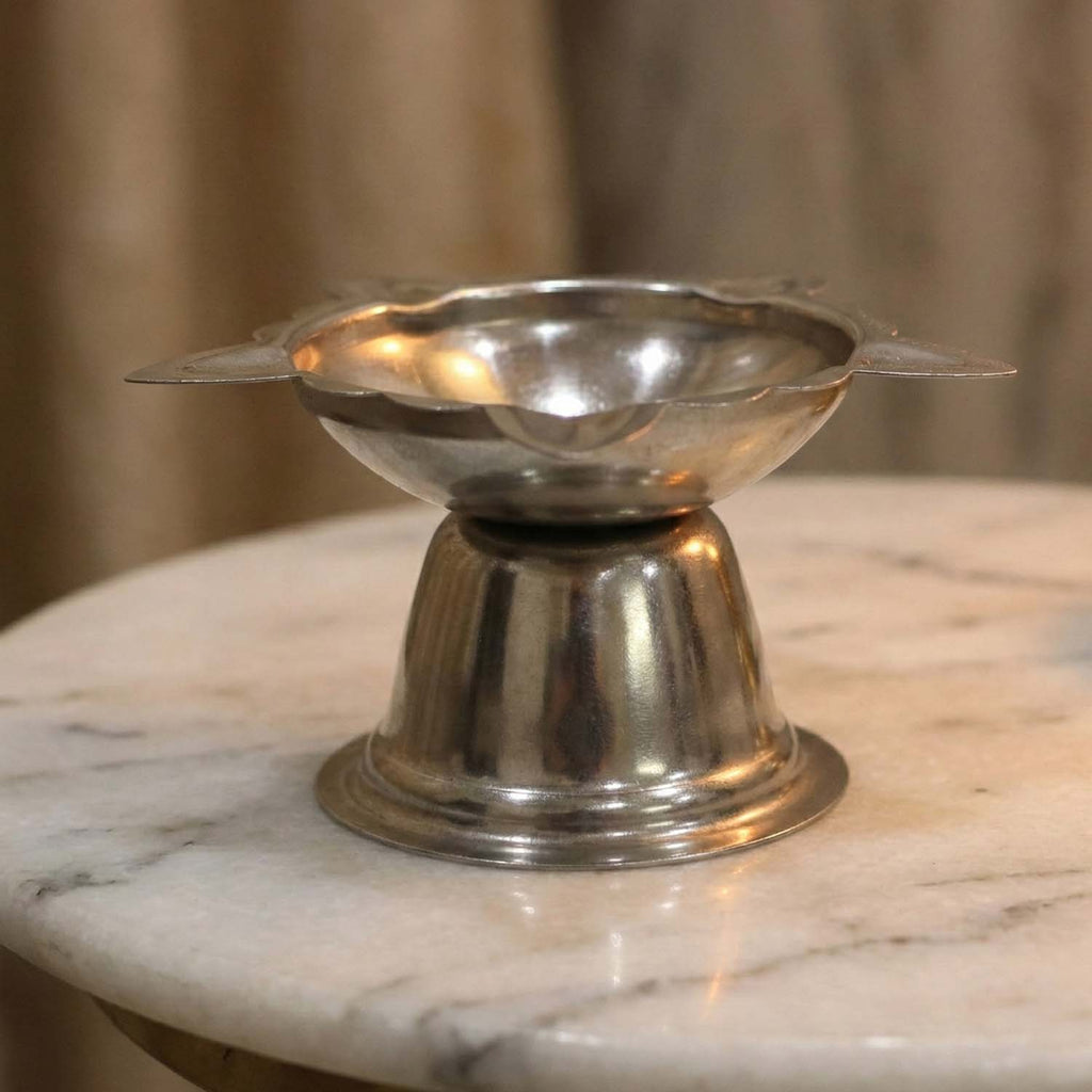 Polished metal diya stand with traditional sunflower pattern