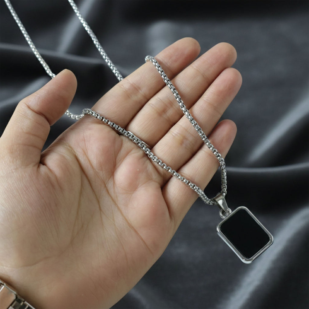 Black rectangular pendant framed in polished metal on men's stainless-steel chain