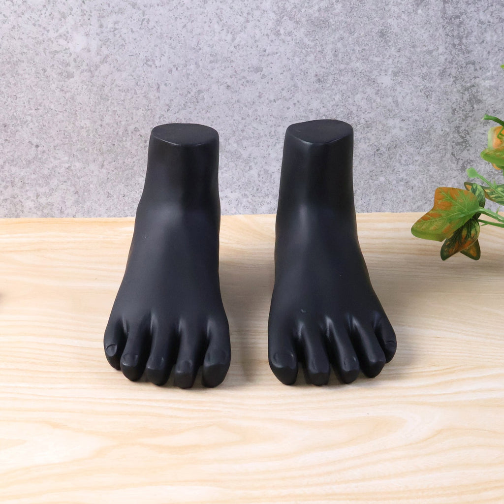 Black foot mannequin stand pair displaying silver anklets against black matte finish