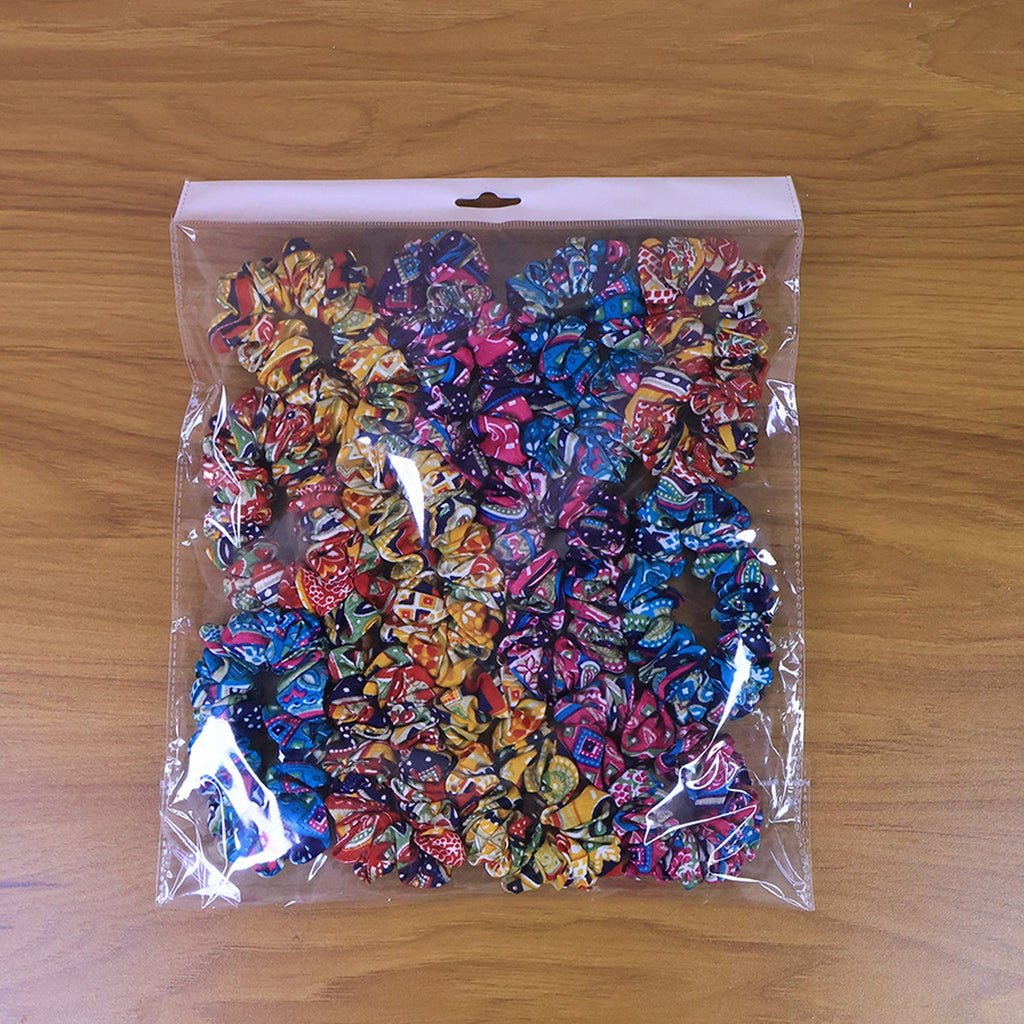 Hand holding multiple colorful printed fabric hair scrunchies