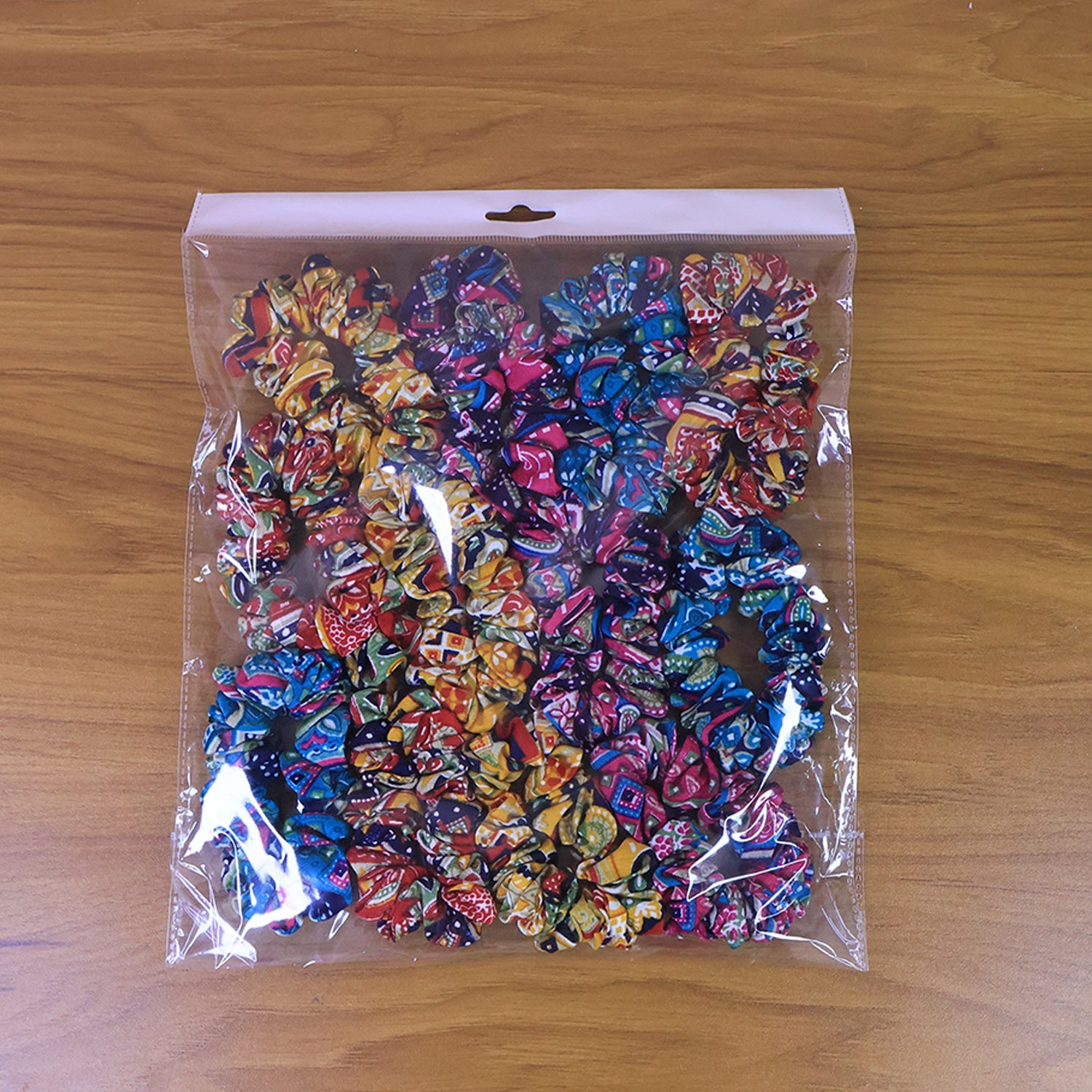 Hand holding multiple colorful printed fabric hair scrunchies