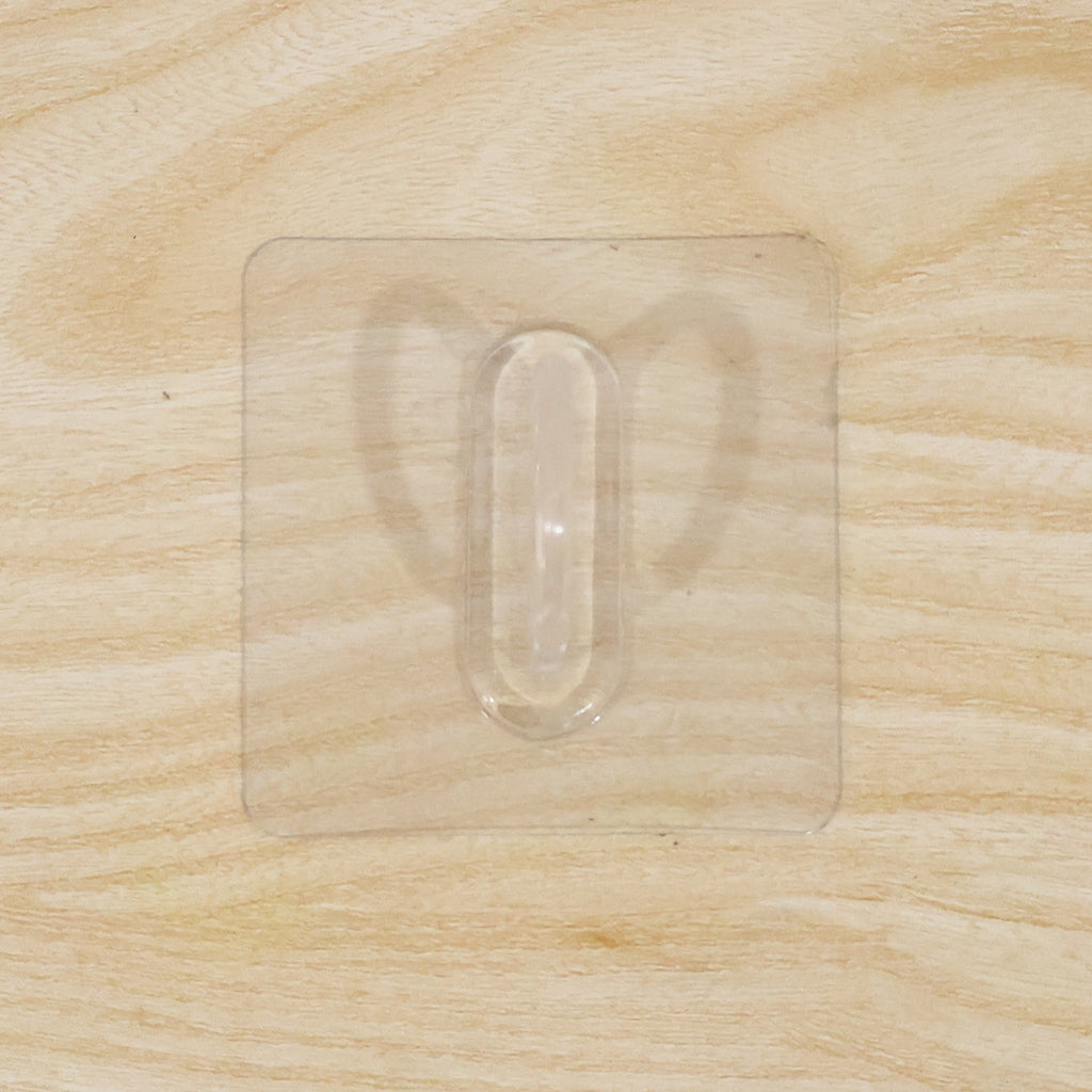 Close-up of transparent wall hook showing its adhesive pad