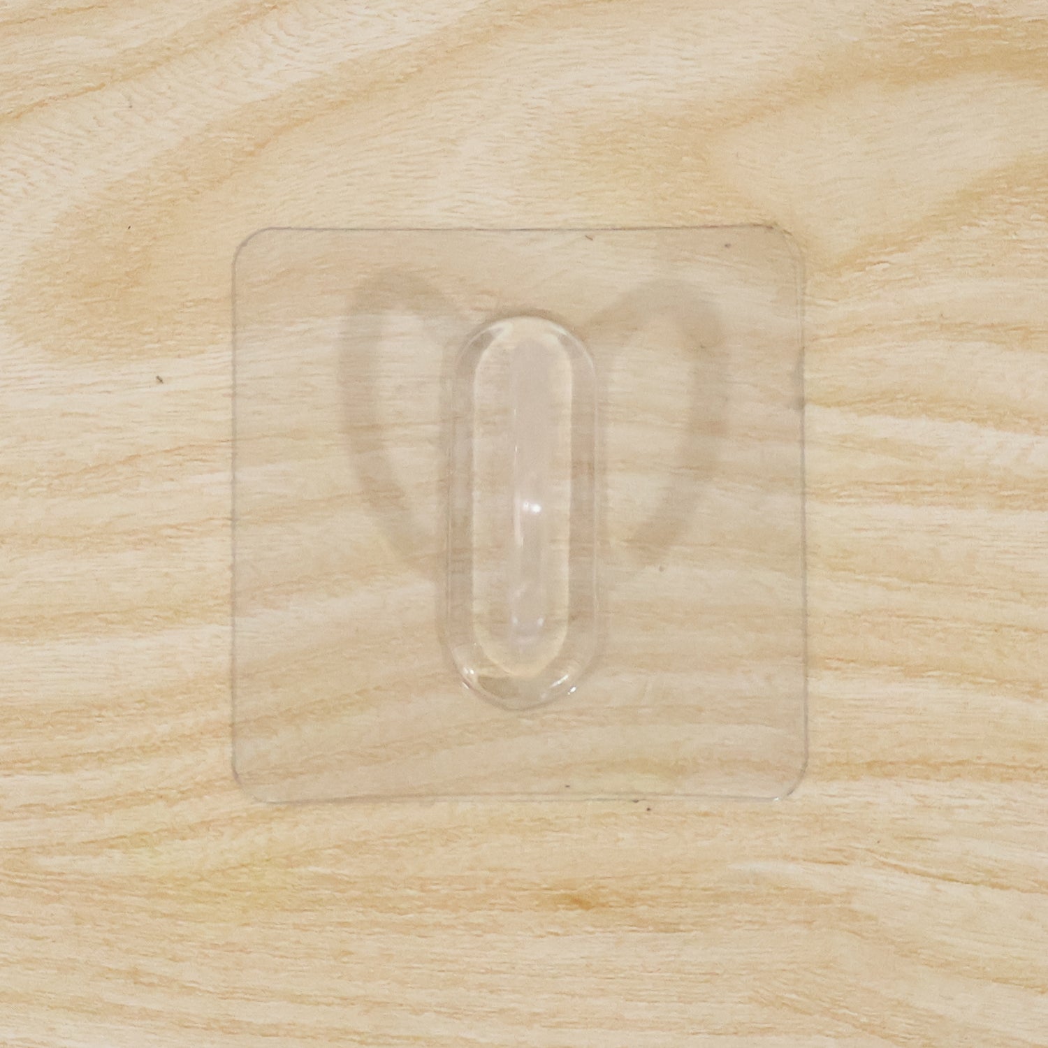 Close-up of transparent wall hook showing its adhesive pad