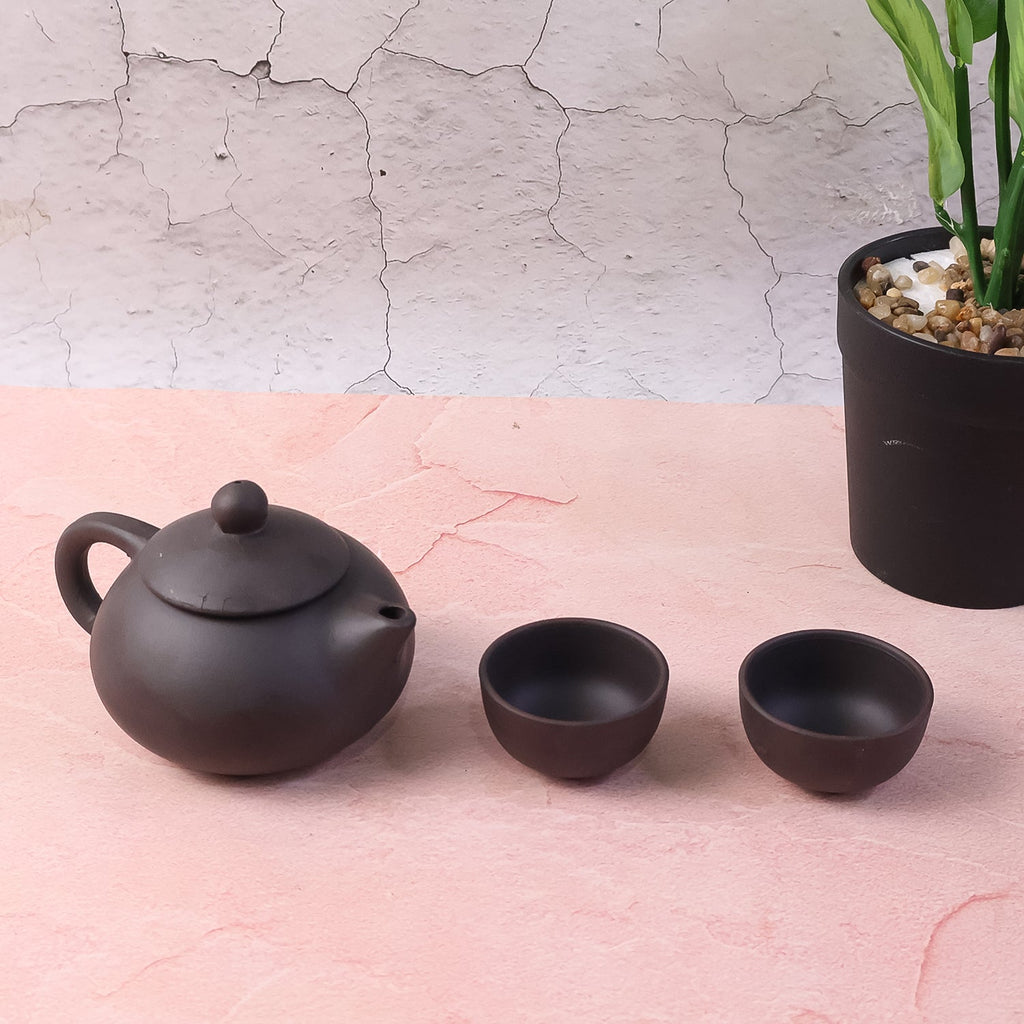 Side view of matte black ceramic tea set with teapot and cups