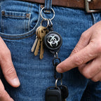 Hand holding a compact retractable keychain with sturdy clip.