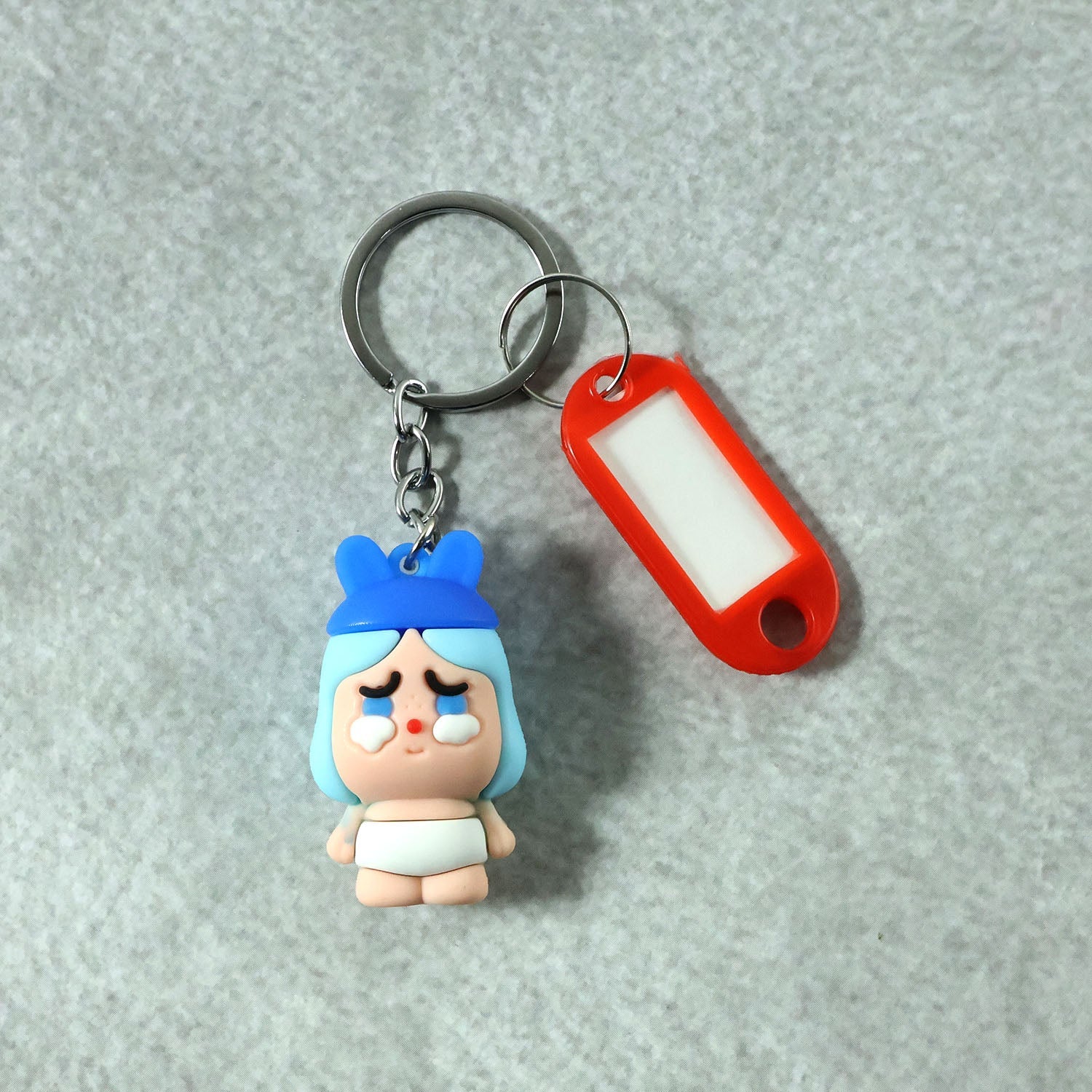 Close-up of cartoon baby figure keychain with metal ring and label tag holder.