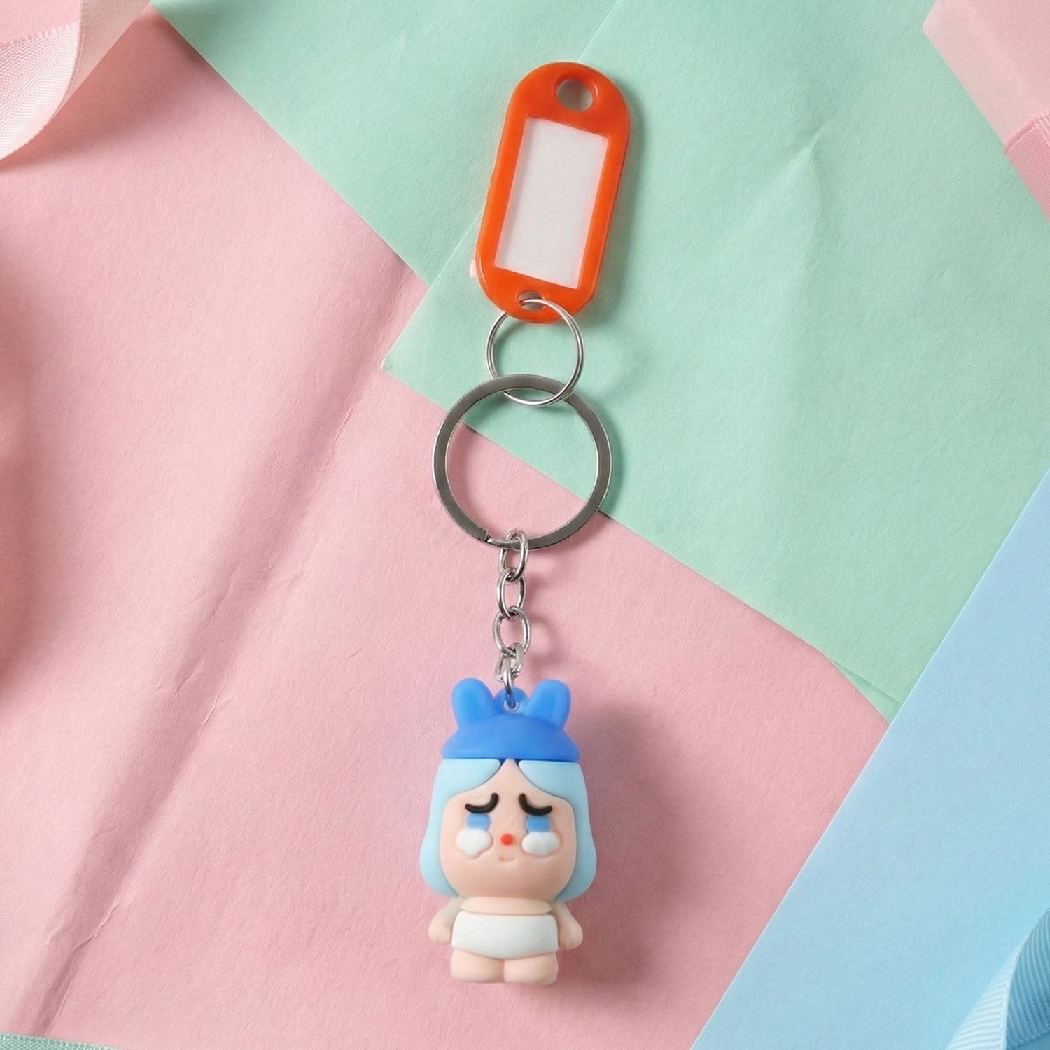 Cartoon baby character keychain attached to bag zipper for easy identification.