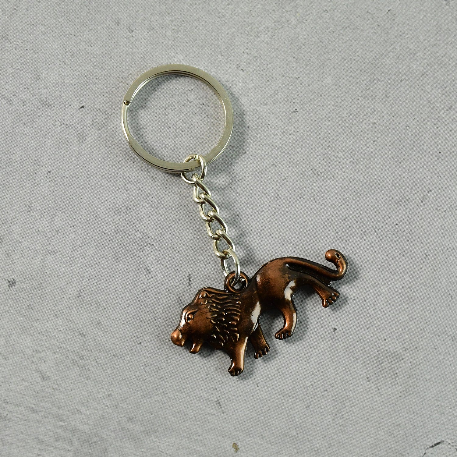 Antique finish metal lion keychain placed on a plain surface