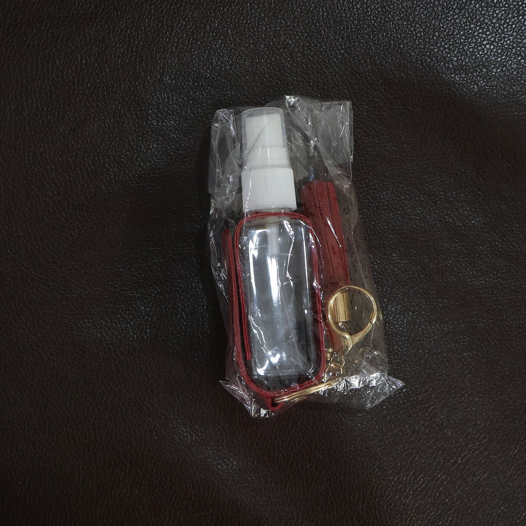 Person holding faux leather hand sanitizer holder keychain with tassel
