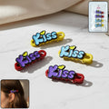 Four decorative Kiss text hair clips arranged on display