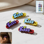 Four decorative Kiss text hair clips arranged on display