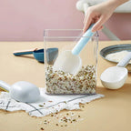 A large plastic measuring spoon shown scooping flour from a bag.