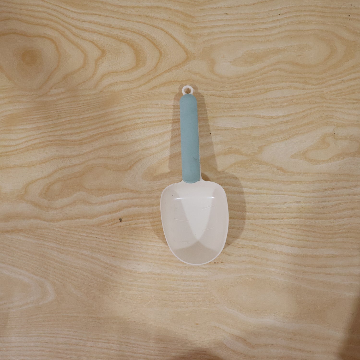 A white plastic measuring spoon demonstrating its use as a bag clip on a food bag.