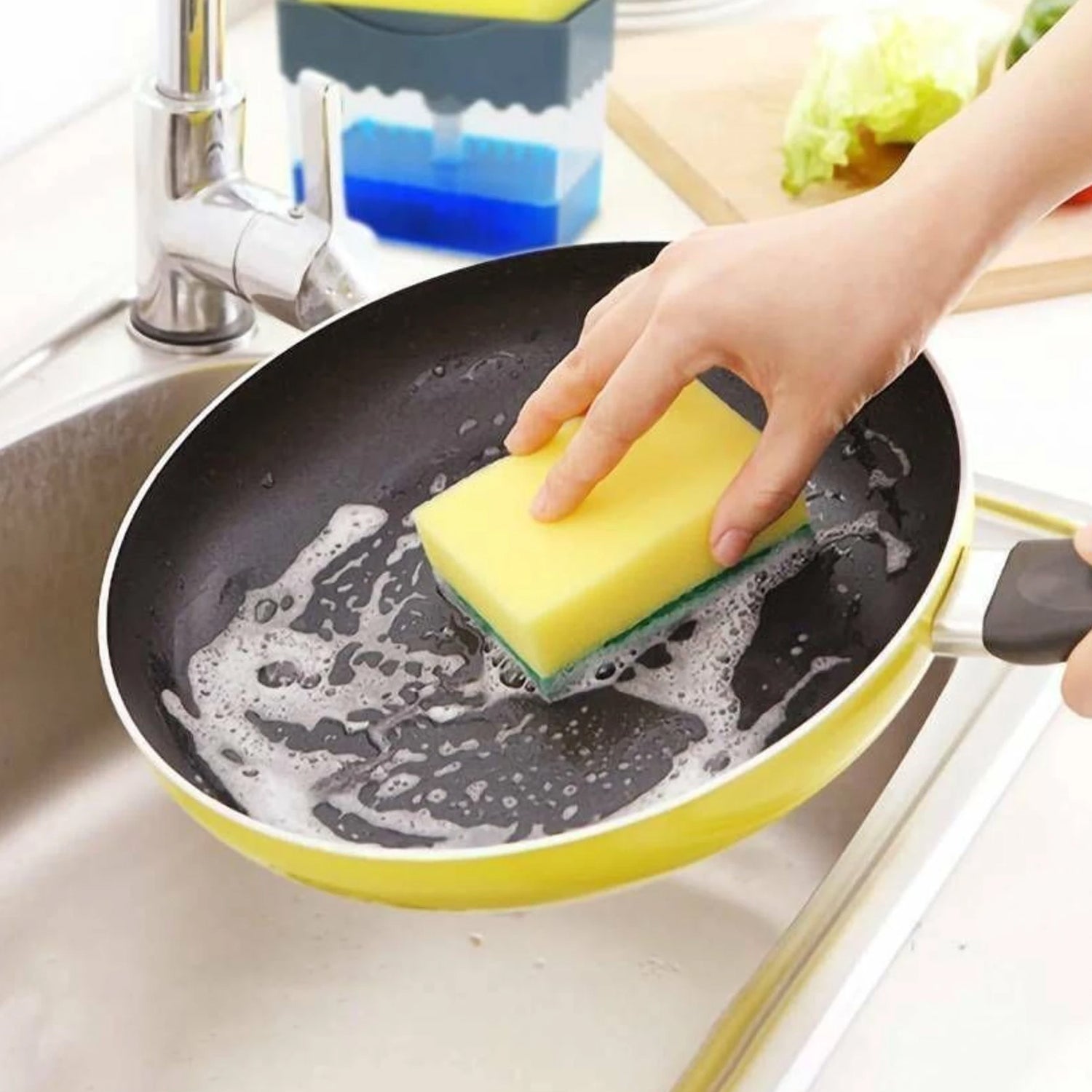 Compact soap dispenser and sponge holder filled with dish soap next to a kitchen sink.