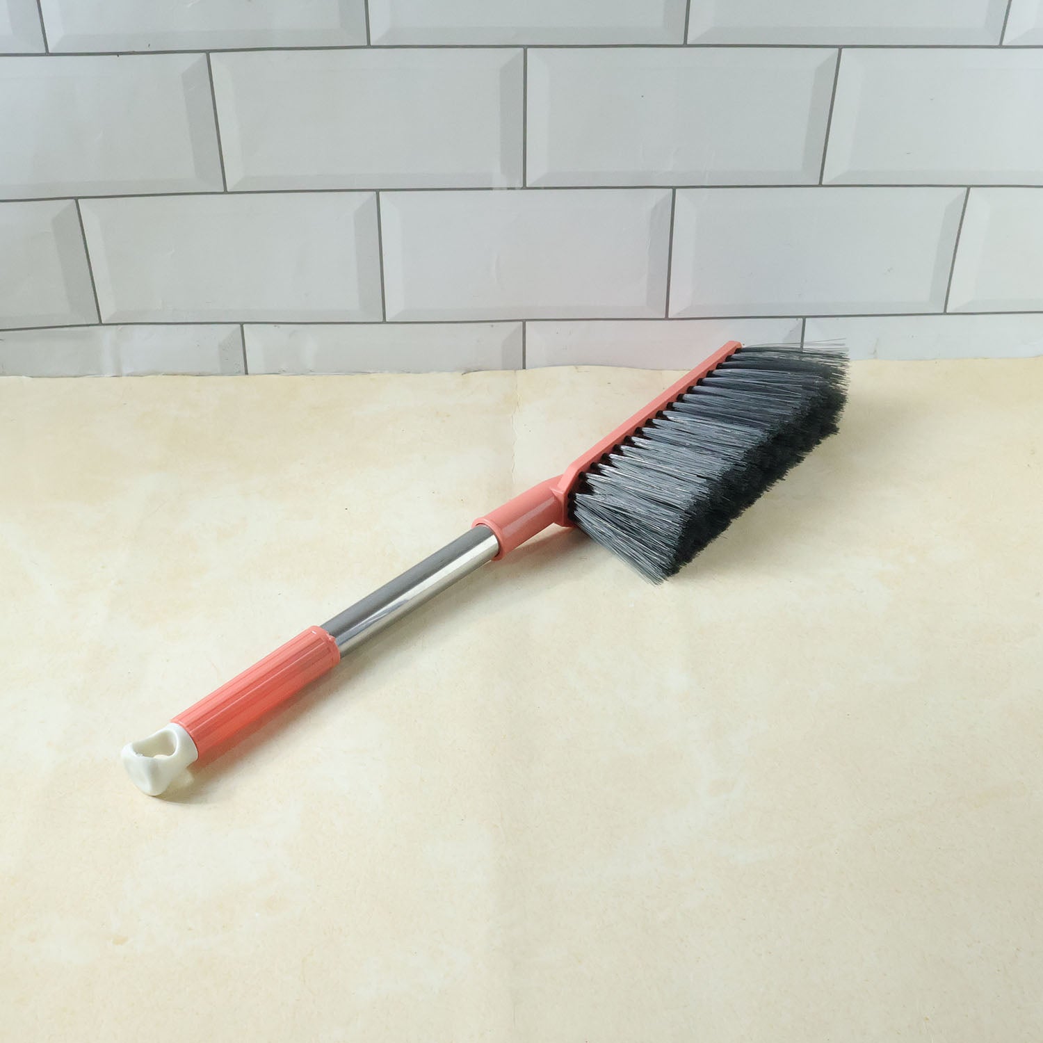 Long handle cleaning brush in use for dusting furniture surfaces