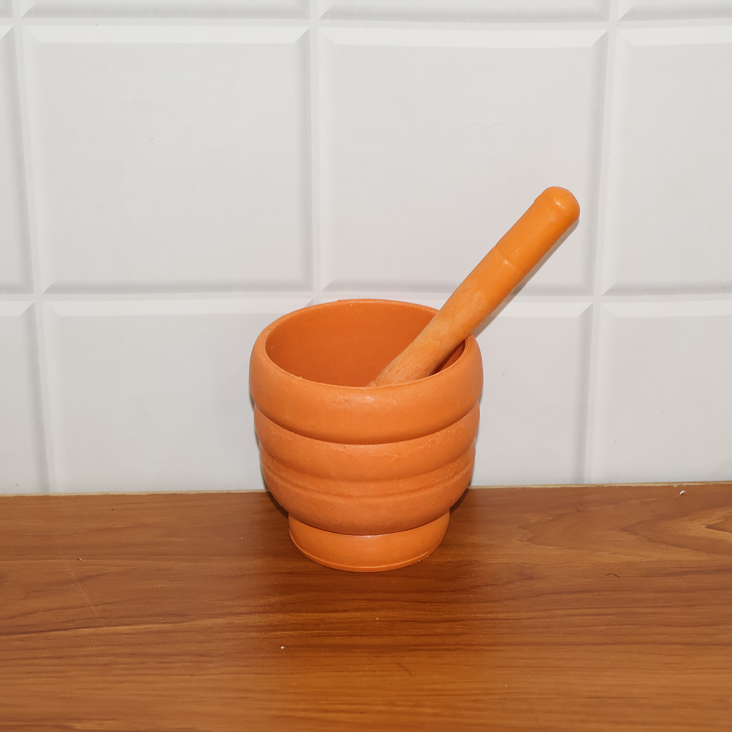 Plastic mortar and pestle set displayed with fresh ginger, garlic, and herbs, illustrating its use as an herb crusher.