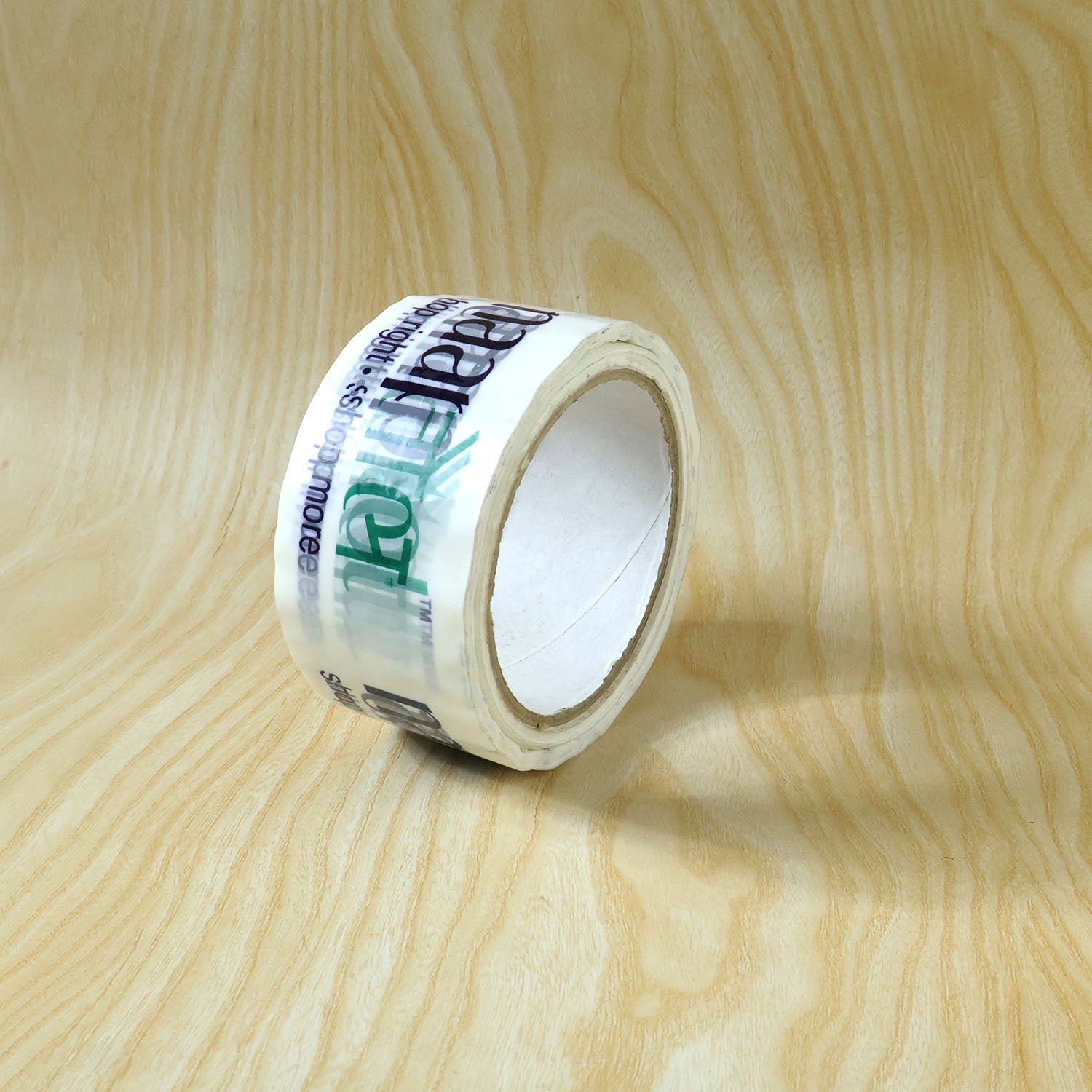 Printed packaging tape roll displayed at an angle, highlighting its strong adhesive quality.