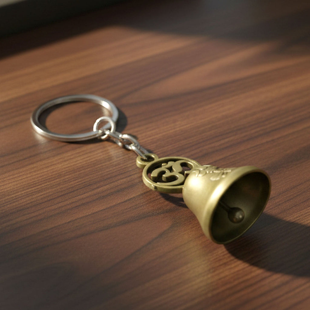 Om temple bell keychain held in hand showing compact size